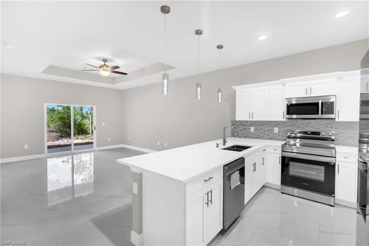 Kitchen featuring stainless steel appliances, a peninsula, a ceiling fan, white cabinets, and open floor plan
