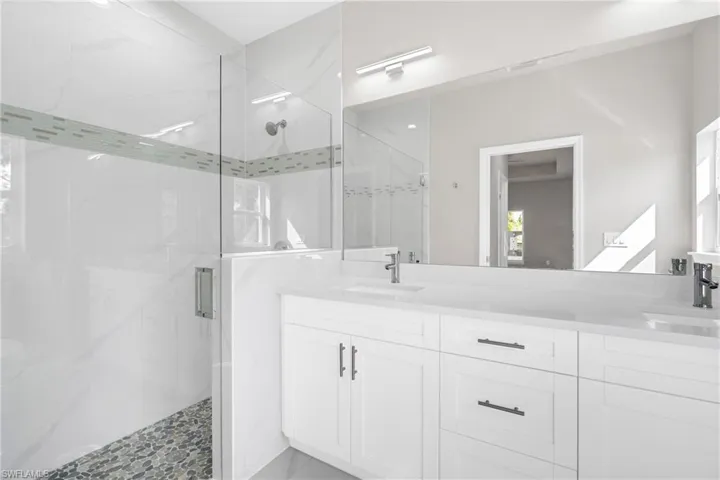 Full bath featuring a marble finish shower and double vanity