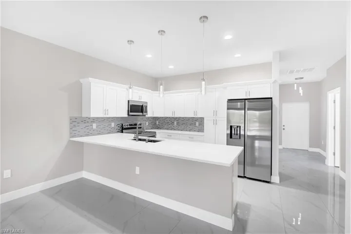 Kitchen with stainless steel appliances, white cabinetry, light marble finish floors, decorative backsplash, and a peninsula