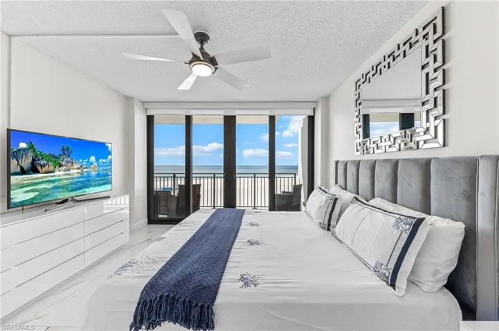 Bedroom featuring expansive windows, access to exterior, ceiling fan, a textured ceiling, and a water view