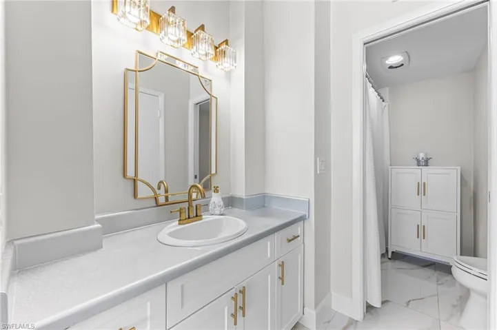 Full bath with light marble finish flooring, vanity, and a shower with shower curtain
