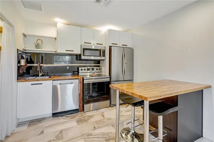 Mother-in-law Suite:  Kitchen with upgraded kitchen appliances, sink, butcher block countertops, decorative backsplash, white cabinets and snack bar.  Walk in pantry on the left.