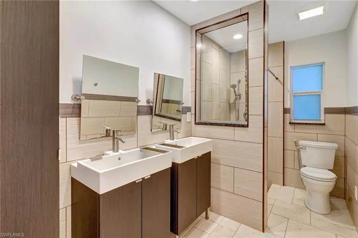 Guest bathroom with doubles vanities, custom mirrors, tiled walls, walk in shower
