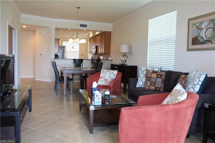 Living area featuring crown molding, light tile patterned flooring, and a chandelier