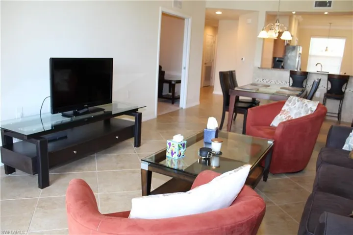 Living room with light tile patterned flooring, a chandelier, and recessed lighting