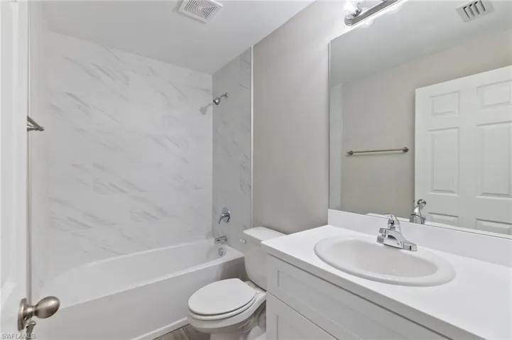 Full bathroom featuring vanity, tiled shower / bath combo, and toilet