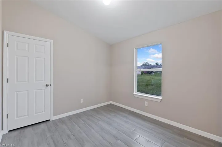 Spare room featuring lofted ceiling and light hardwood / wood-style flooring