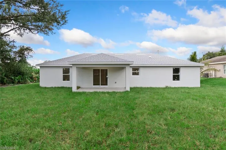Rear view of house featuring a patio and a lawn