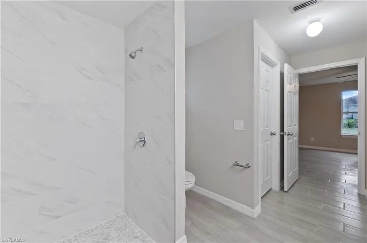 Bathroom featuring a tile shower and toilet