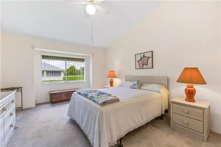 Carpeted bedroom with high vaulted ceiling and ceiling fan