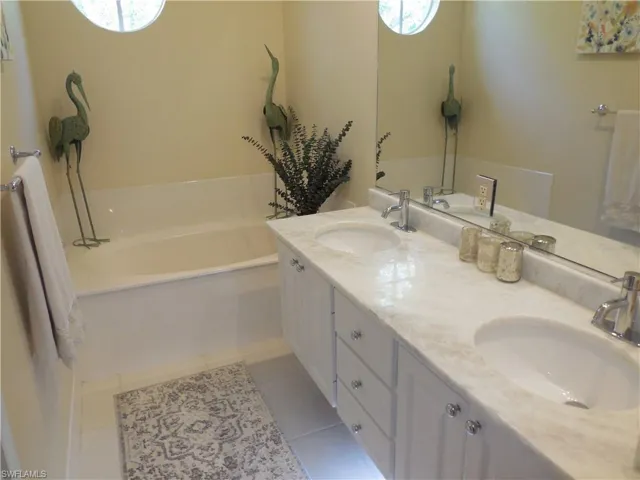 Bathroom with tile patterned floors, a bath, healthy amount of natural light, and double vanity