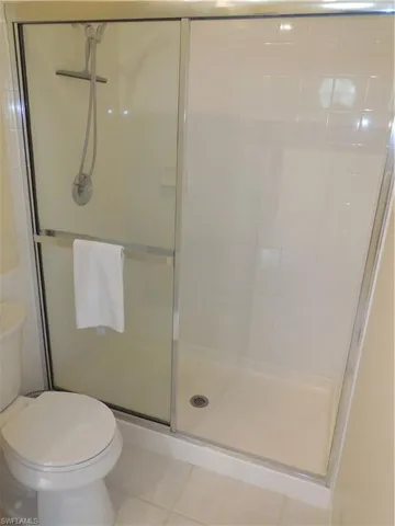 Full bathroom featuring a shower with door and toilet