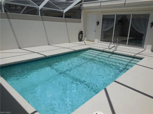 Swimming pool with a patio and glass enclosure