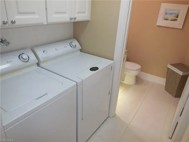 Laundry room with washer and dryer, light tile patterned flooring, and baseboards
