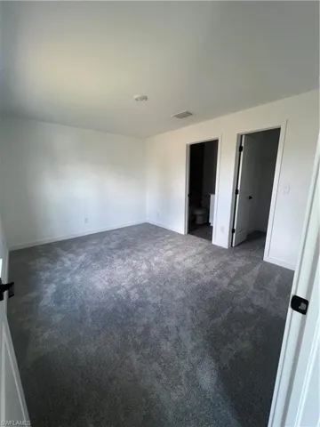 Empty room featuring dark colored carpet