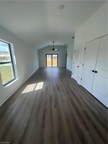 Unfurnished living room featuring ceiling fan, lofted ceiling, and dark hardwood / wood-style flooring