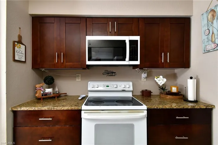 Kitchen featuring dark wood-finish cabinetry, light-toned countertops, and a built-in microwave above the range