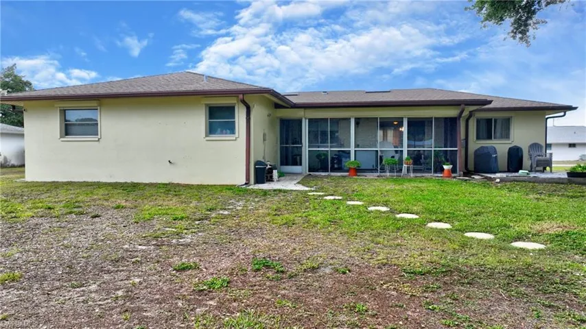 Rear exterior featuring a screened patio, shingled roof, stucco siding, and rain gutters