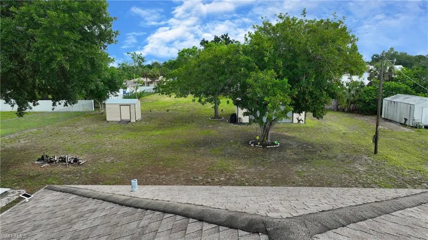 Expansive backyard featuring mature trees, two storage sheds, and a partial perimeter fence