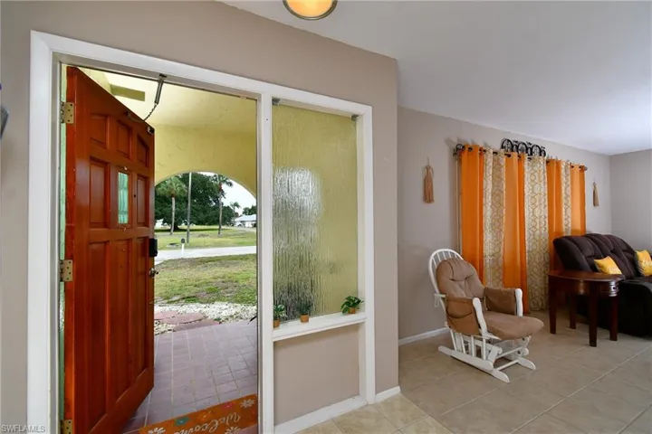 Entryway featuring a paneled wooden door, textured glass sidelight, and tiled flooring