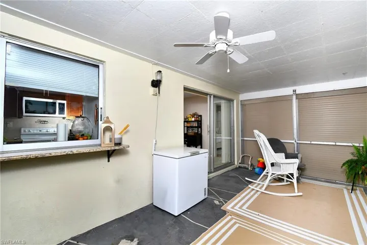 Enclosed patio featuring a ceiling fan, sliding glass doors, pass-through window with a stone-finish sill, and roll-down screens
