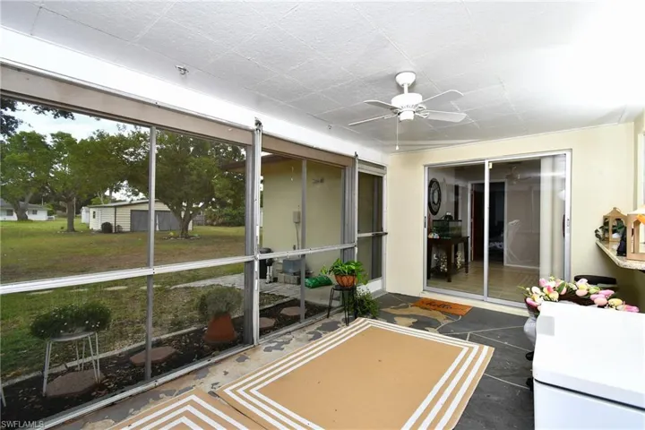 Screened porch featuring stone-finish flooring, a ceiling fan, and sliding glass doors