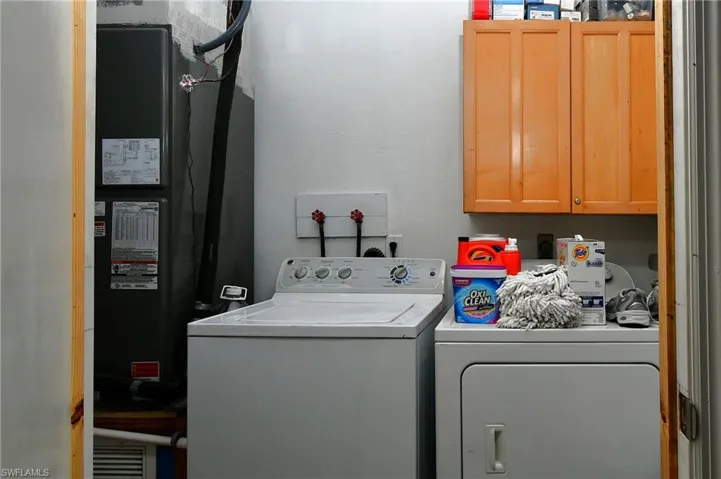 Dedicated laundry area featuring overhead cabinetry, a water heater, and a washer/dryer hookup