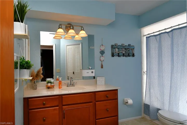 Bathroom vanity featuring a light countertop, wood-finish cabinetry, and a four-light fixture