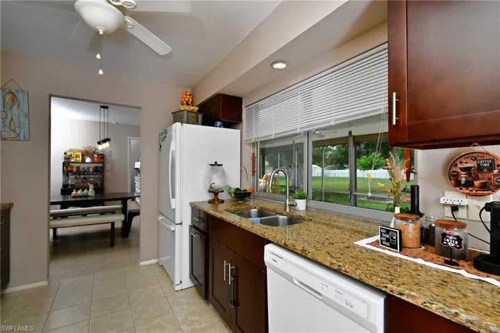 Kitchen featuring a double basin stainless steel sink, granite countertops, and dark wood cabinetry