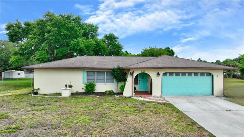 Single-story residence featuring a two-car garage with a teal door, a matching teal front door, and stucco exterior