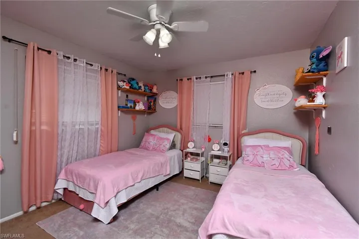 Room featuring light gray walls, two windows with blinds, a ceiling fan with integrated lighting, and carpet flooring
