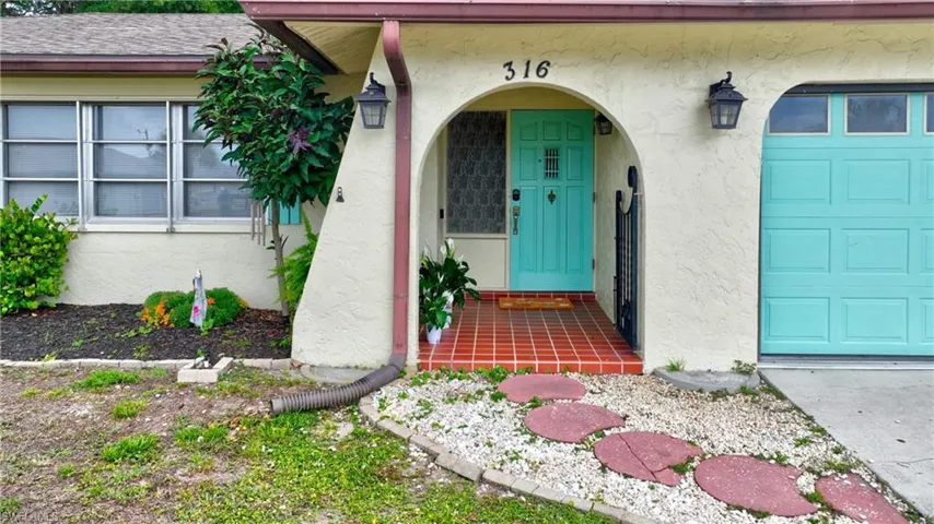 Front exterior showcasing a stucco finish, arched entryways, and a light turquoise front door and garage door