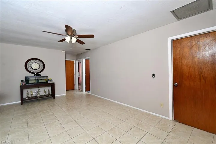 Spacious room featuring neutral wall paint, square tile flooring, and a ceiling fan with integrated lighting