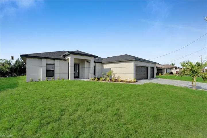 View of front of home with concrete driveway, an attached garage, a front lawn, and stucco siding