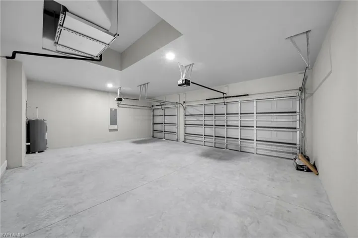Garage featuring a garage door opener, water heater, electric panel, and recessed lighting