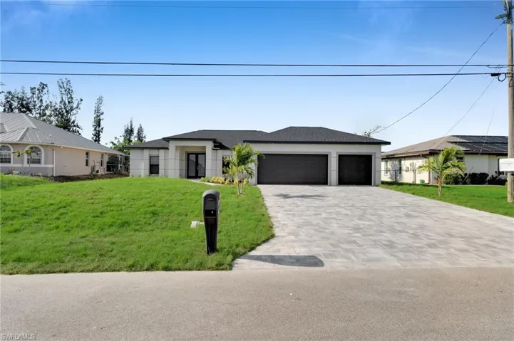 View of front of property with decorative driveway, a garage, a front lawn, and stucco siding