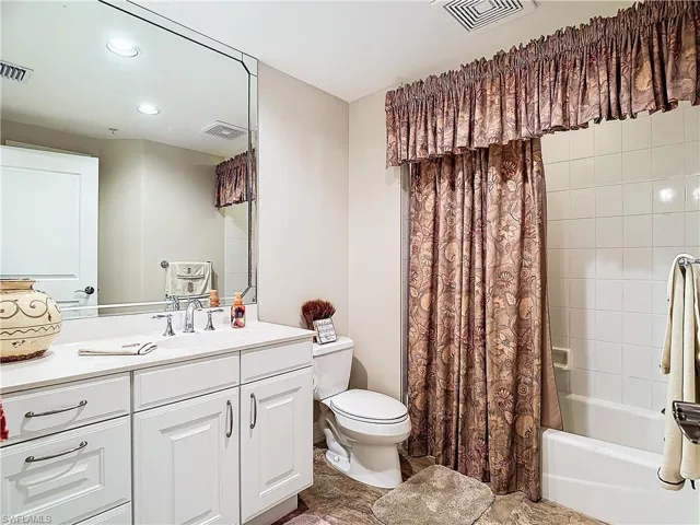 Full bathroom with toilet, vanity, and shower / bath combination with curtain