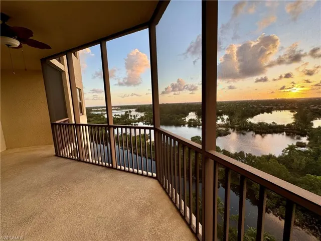 Balcony at dusk featuring a water view and ceiling fan