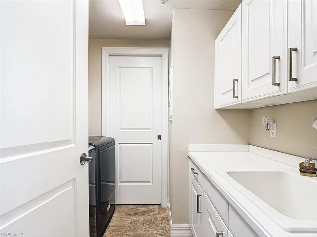 Laundry room featuring sink, washing machine and clothes dryer, and cabinets