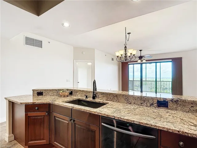 Kitchen with ceiling fan with notable chandelier, sink, black dishwasher, hanging light fixtures, and light stone counters