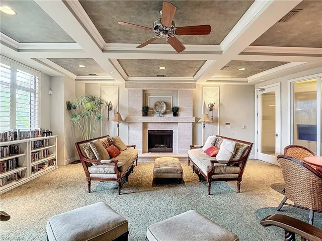 Living room with beamed ceiling, light colored carpet, a tile fireplace, crown molding, and coffered ceiling