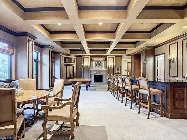 Dining space featuring coffered ceiling, wood walls, crown molding, and light carpet