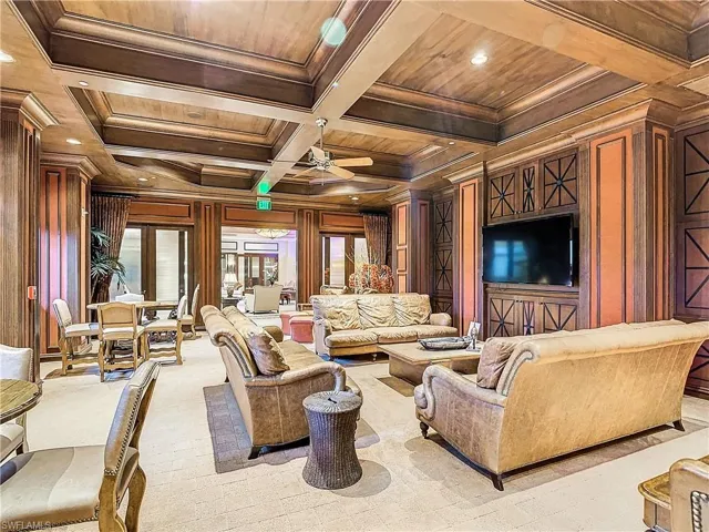 Living room featuring wood walls, coffered ceiling, wooden ceiling, crown molding, and beam ceiling