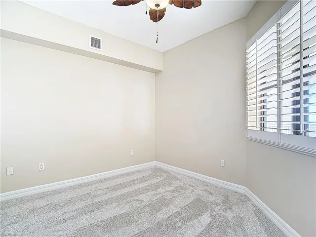 Spare room featuring ceiling fan, a wealth of natural light, and carpet flooring