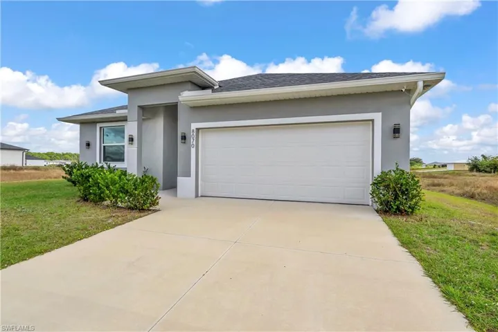 View of front of home featuring a shingled roof, stucco siding, concrete driveway, and an attached garage
