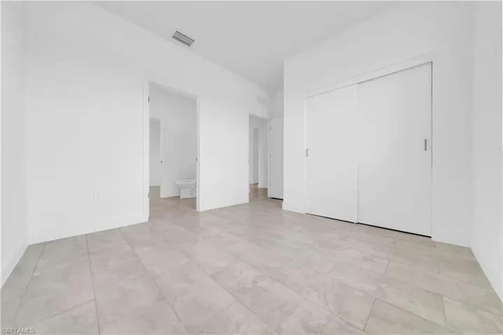 Unfurnished bedroom with ensuite bath and a closet
