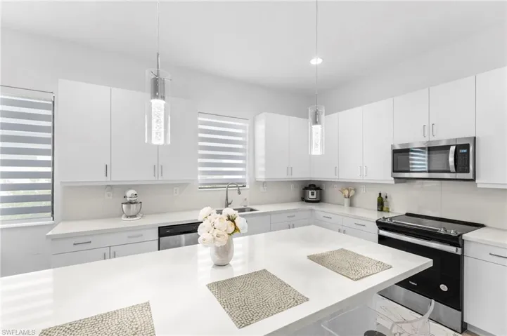Kitchen featuring white cabinets, pendant lighting, sink, and stainless steel appliances