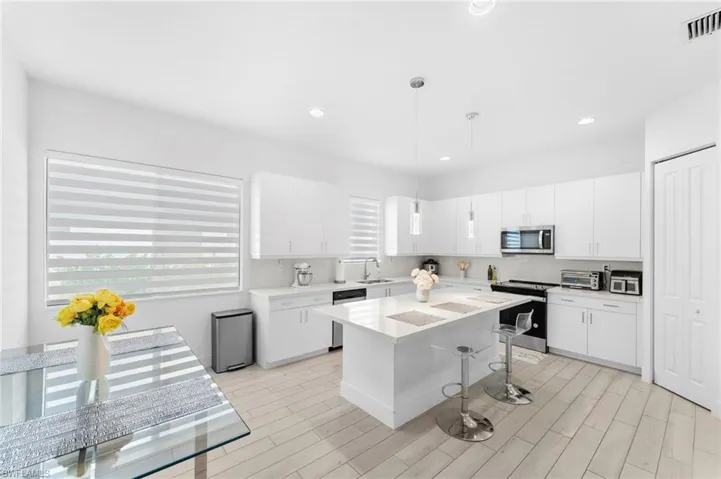 Kitchen with pendant lighting, sink, white cabinetry, and stainless steel appliances