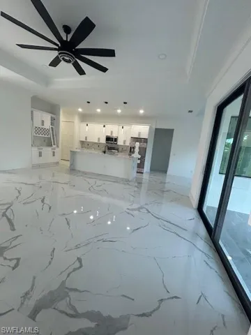 Unfurnished living room featuring light marble finish flooring, recessed lighting, and a raised ceiling