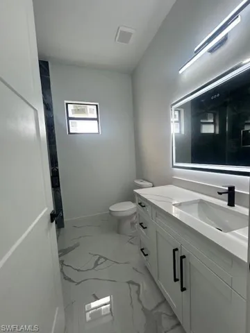 Bathroom featuring light marble finish flooring and vanity